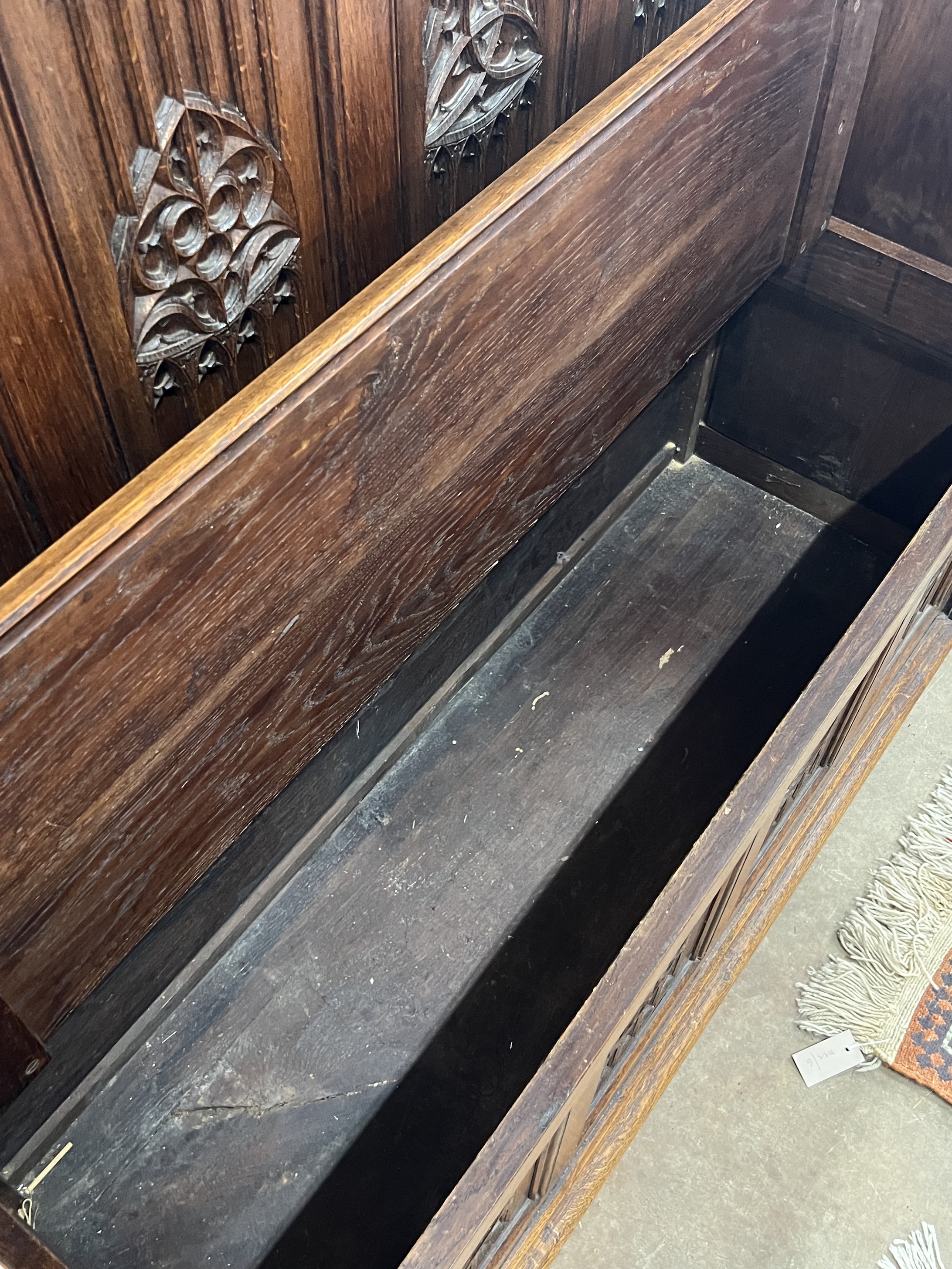 An early 20th century carved oak Gothic Revival settle with hinged box seat, width 137cm, depth 49cm, height 160cm